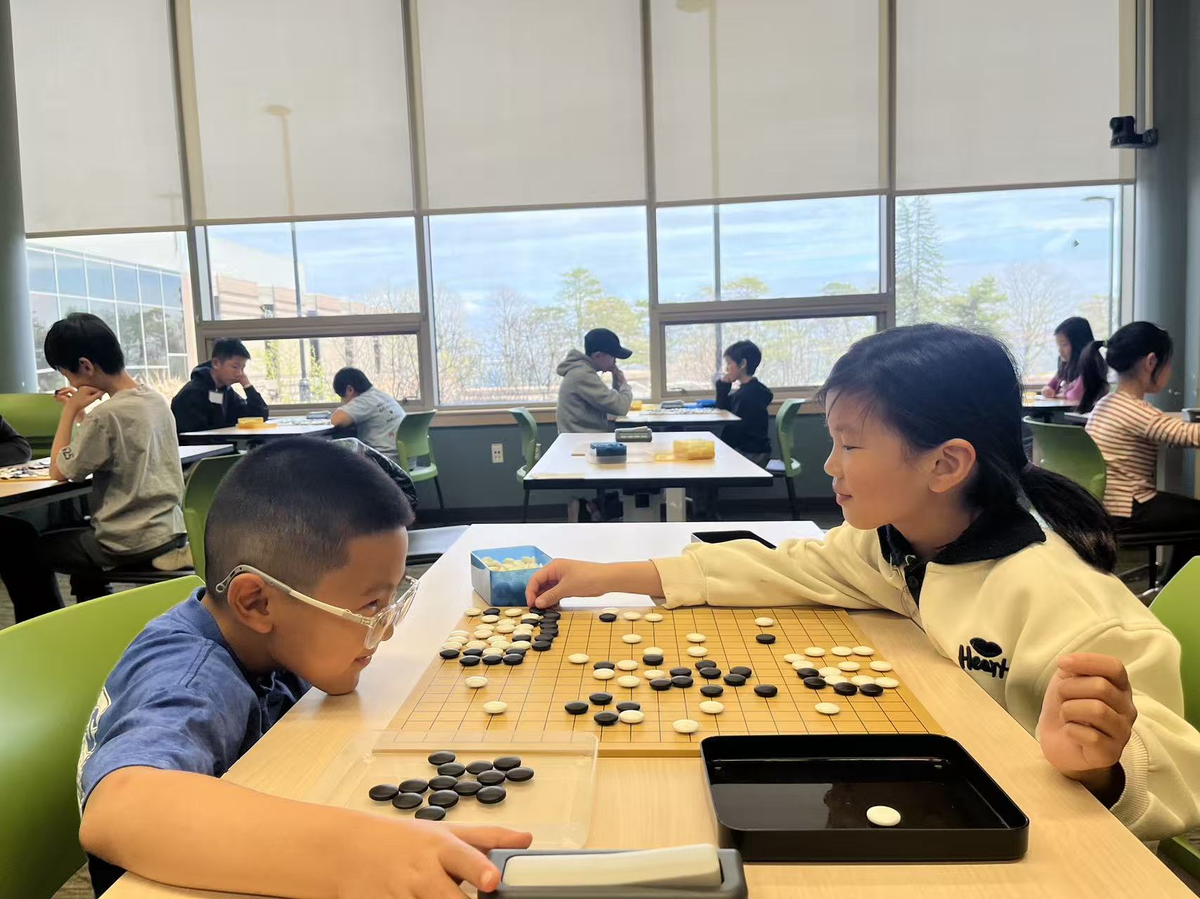 Young Go players enjoying a game during a community event
